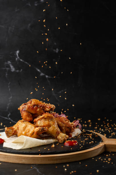 ali di pollo di bufalo al forno con semi di sesamo, cipolla e fette di peperoncino su tavola di legno nero - roasted sesame seeds foto e immagini stock