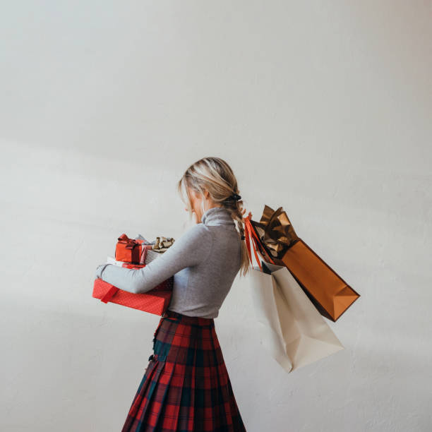 une femme anonyme tenant des cadeaux de noël dans ses mains - women holding shopping bag living room photos et images de collection
