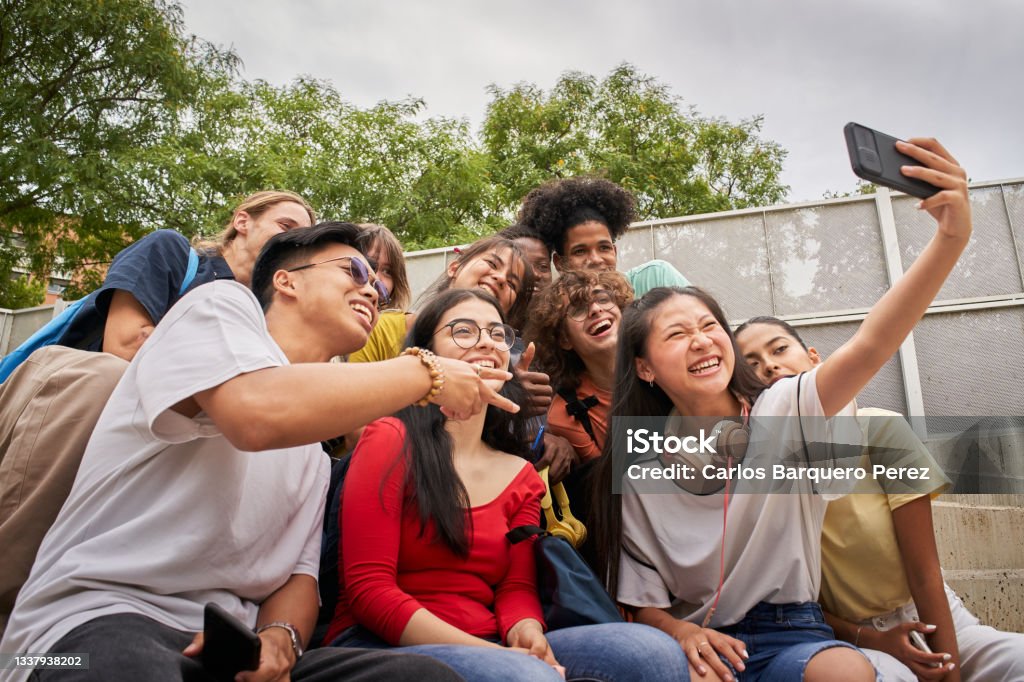 Group of multi-ethnic students taking selfies with mobile phone. Teenagers using a smart phone and having fun together. Teenagers Only Stock Photo