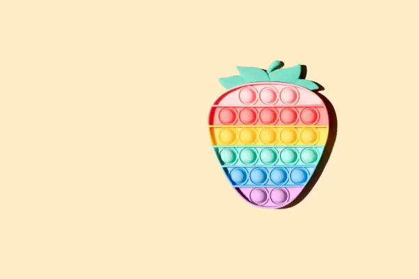 Photo of Antistress rainbow pop-it toy strawberry beige background.