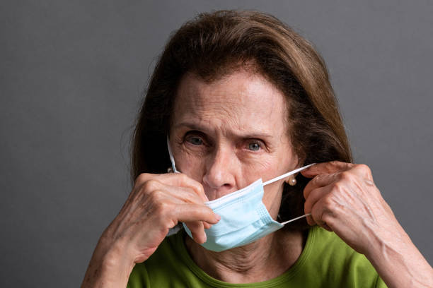 istock Senior woman wearing and adjusting protective face mask 1337943773