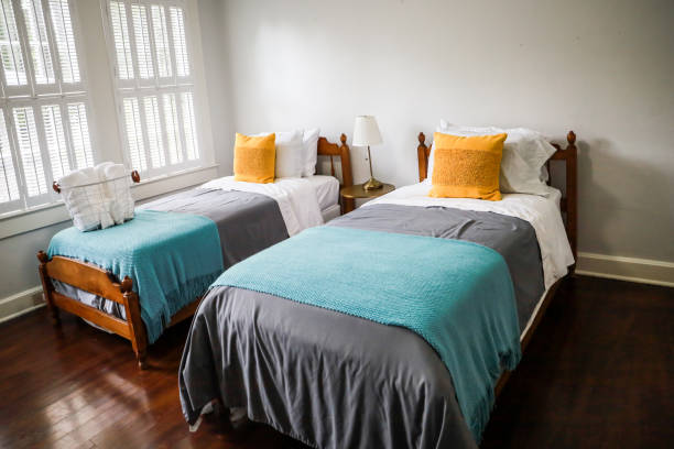 A guest bedroom with two twin beds with turquoise and gray bedspreads and yellow decorative pillows A guest bedroom with two twin beds with turquoise and gray bedspreads and yellow decorative pillows. twin bed stock pictures, royalty-free photos & images