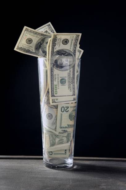 istock High glass full of dollar notes over black 1337947109