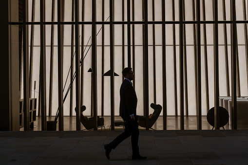 Worker passing by empty offices in the City of London with sunset lights