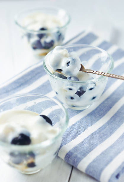 Yogurt with honey and fresh bilberries on bright background. Close up.