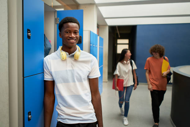 ritratto di uno studente nero che guarda la macchina fotografica sorridente a scuola. - child student adolescence cute foto e immagini stock