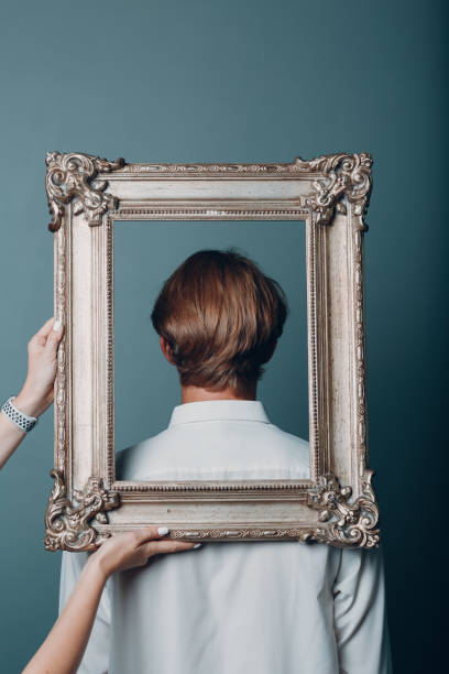 istock Portrait young man standing with picture frame at studio. 1337955844