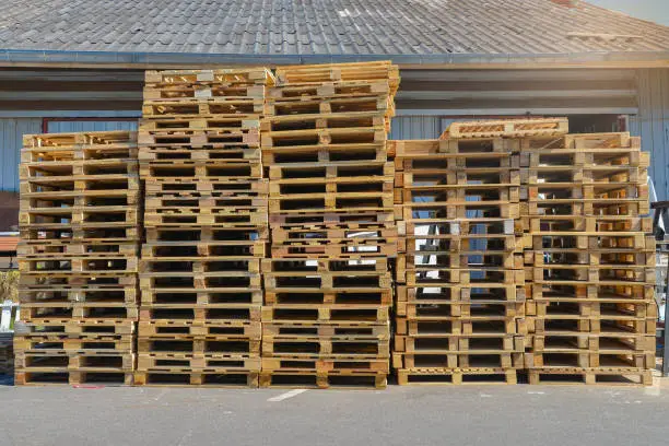 A stack of pallets sit outside a building, Wooden pallet.