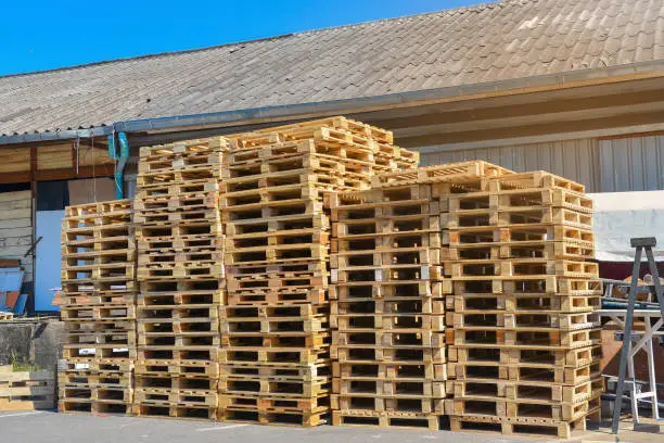 A stack of pallets sit outside a building, Wooden pallet.