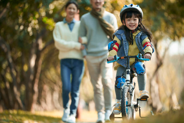 familia asiática joven con un niño disfrutando de la salida en el parque - helmet bicycle little girls child fotografías e imágenes de stock