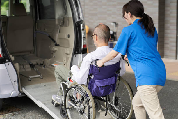 A caregiver who puts an elderly person in a long-term care taxi A caregiver who puts an elderly person in a long-term care taxi wheelchair stock pictures, royalty-free photos & images