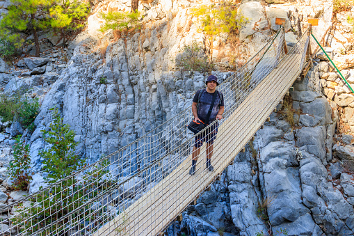 Young man standing on suspension wooden bridge in Goynuk canyon in Antalya province,Turkey