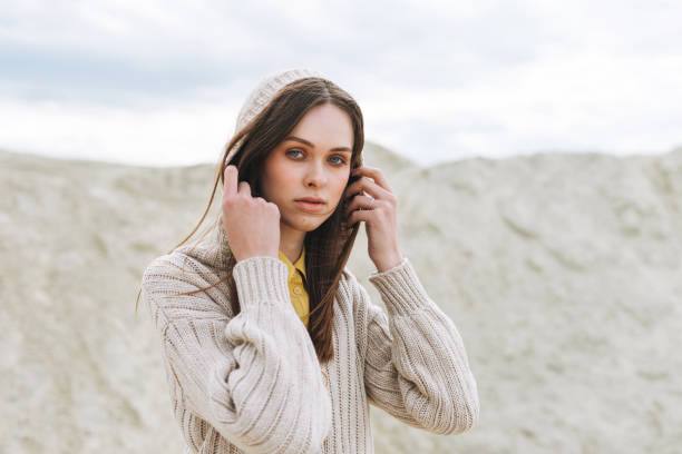 fashion beauty portrait of young woman with long hair in knitted cardigan on desert background, autumn outfit - hot couture imagens e fotografias de stock