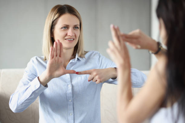 istock Two young happy women sitting on couch and making sign languages 1337998402