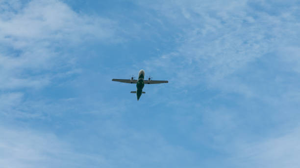 istock View of propeller plane fly low with blue sky and clouds at background. 1338004378