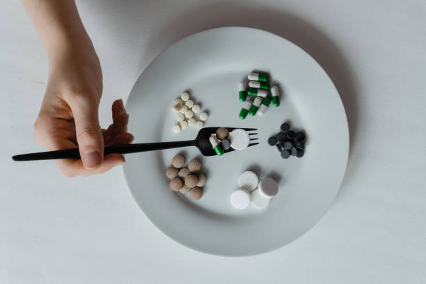 istock nutritional supplement pills and tablets on white plate with black fork and knife 1338005189