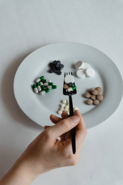 istock nutritional supplement pills and tablets on white plate with black fork and knife 1338005195