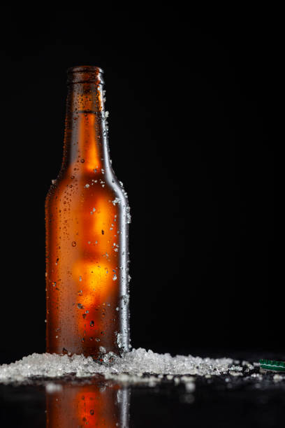 istock Ice Cold Brown Beer Bottle Covered with ice and water drops - condensation. Blank for drink beverage product design mock-up.  Standing on black table with dark - black background. 1338005646