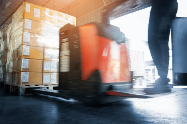 istock Motion Blur of Worker Driving Electric Forklift to Unloading Package Boxes at the Warehouse. 1338006625