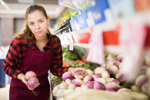 istock Young saleswoman  lays rutabaga on a showcase 1338007778