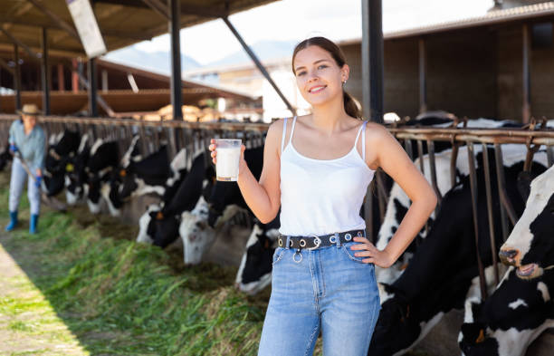 mungitrice femminile in posa con un bicchiere di latte nel caseificio - milker foto e immagini stock