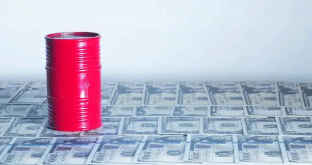 Photo of A Barrel of oil. A physical container used to transport crude oil, on top of American bills.Concept: Oil Prices