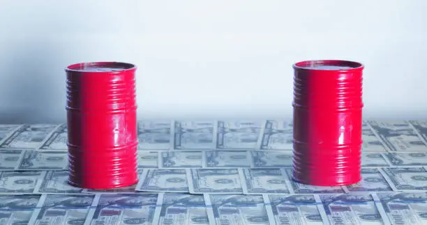 Photo of A couple of Barrel of oil. A physical container used to transport crude oil, as most petroleum is moved. On top of American bills.Concept: Oil Prices