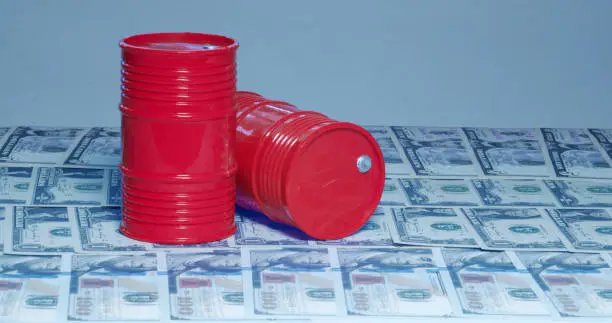 Photo of A Barrel of oil. A physical container used to transport crude oil, on top of American bills.Concept: Oil Prices