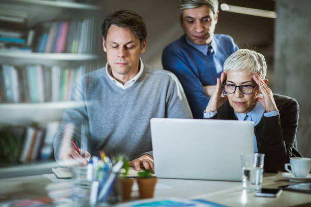 business team cooperating while working on laptop in the office. - looking through window businessman problems reading imagens e fotografias de stock