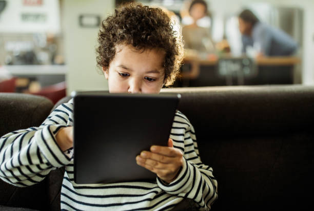 istock Small black boy watching cartoons on touchpad at home. 1338013217