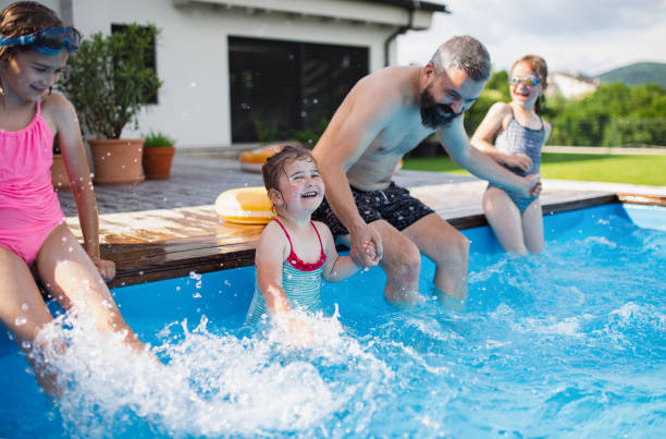 istock Father with three daughters outdoors in the backyard, playing in wimming pool. 1338013225