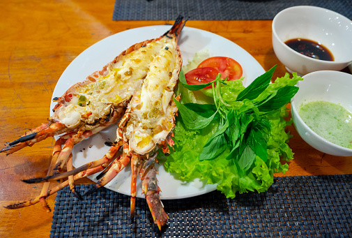 closeup half-cut grilled lobster with butter on table with seafood sauce
