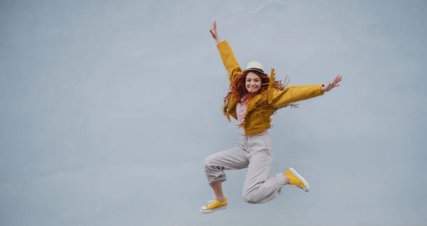 istock Cheerful young woman outdoors against white background, jumping. 1338017623