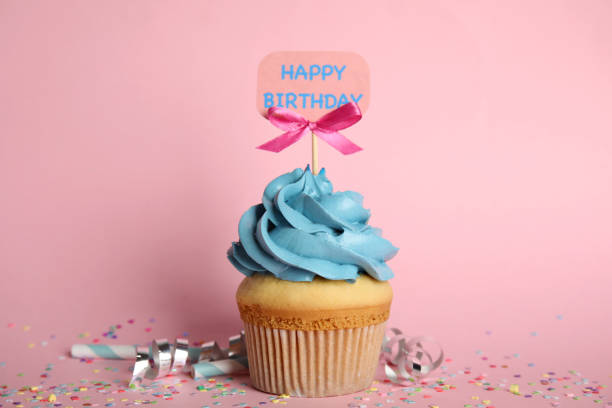 istock Beautiful birthday cupcake, streamers and confetti on pink background 1338017658