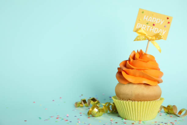 istock Beautiful birthday cupcake, streamers and confetti on light blue background. Space for text 1338017735