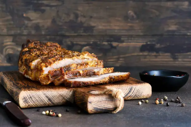 Baked boiled pork.Baked meat slice with garlic and spices on a wooden board.