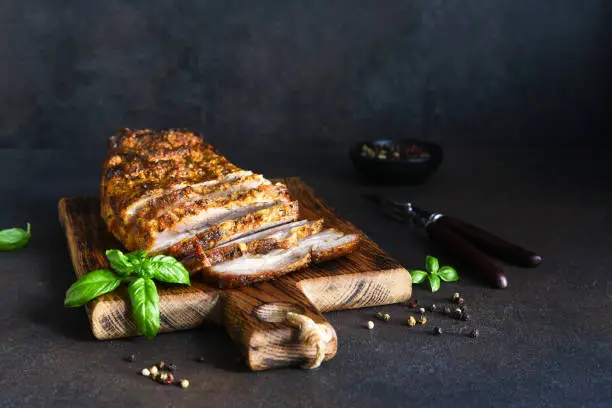 Baked boiled pork.Baked meat slice with garlic and spices on a wooden board.