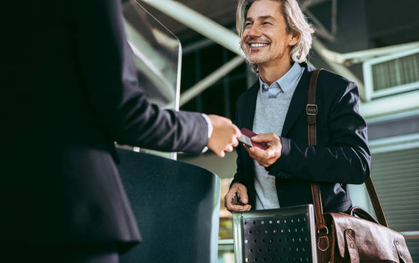 Businessman doing check in at airport Male business traveler at airport boarding gate showing his flight ticket to ground staff. Businessman doing check in at airport. business travel stock pictures, royalty-free photos & images
