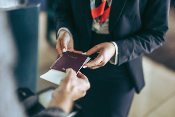 bodenpersonal überprüft reisepass des touristen am flughafen - reisepass stock-fotos und bilder