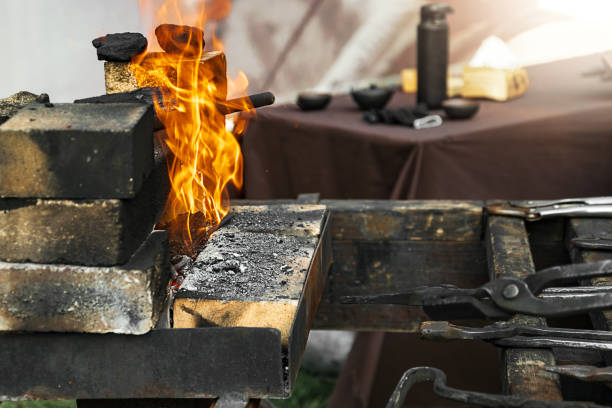 istock Different blackened metal tools of the blacksmith lie in front of burning fire 1338026152