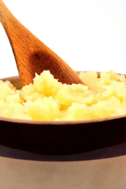 Bowl of mashed potatoes with a wooden spoon in close-up
