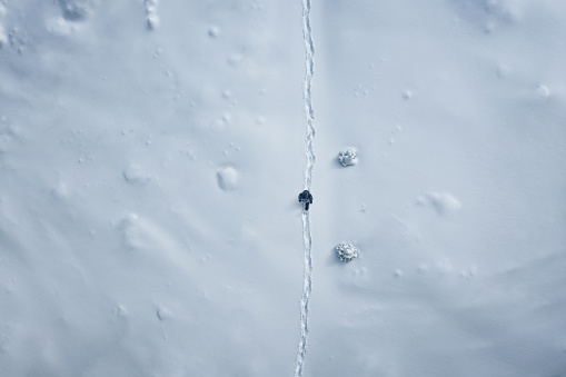 Aerial view on a woman hiking through the fresh snow