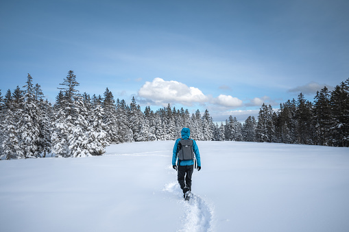 Man hiking through the fresh snow on remote glade in the mountains.