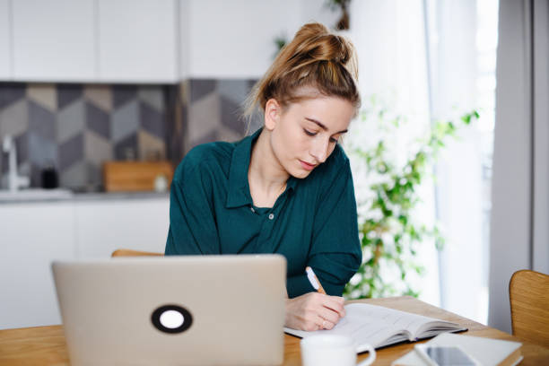 istock Young woman student with laptop writing notes, home office and learning. 1338029266