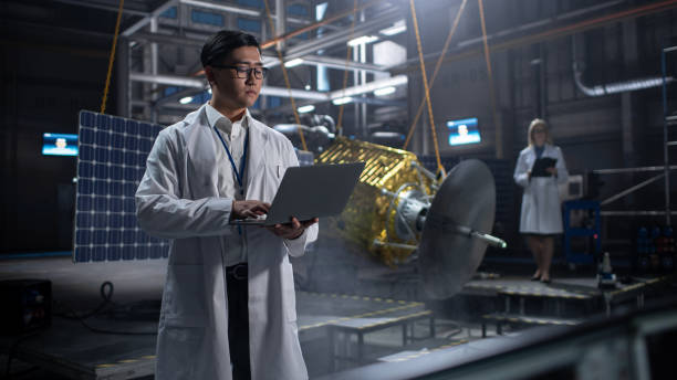 istock Industrial Engineer Working on Artificial Satellite Construction. Aerospace Agency: Asian Scientist Using Laptop Computer to Develop Spacecraft for Space Exploration and Data Communication. 1338031139