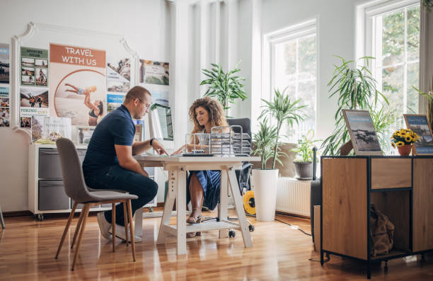 Man planning summer vacation Two people, man in modern travel agency talking with female travel agent, he is planning a vacation.. travel agency stock pictures, royalty-free photos & images