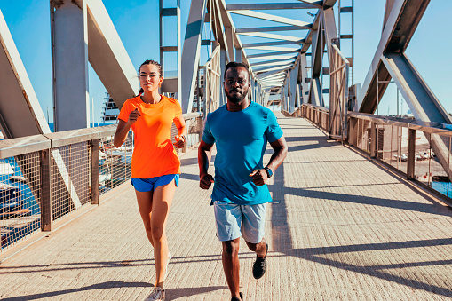 Multi ethnic couple jogging on the street. Couple training outdoors. African american man and caucasian woman doing sport.