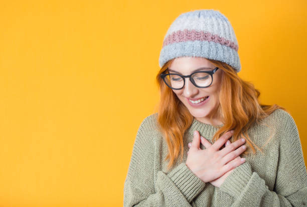 Grateful young woman looking down, isolated on yellow background. Thank you concept. Glad woman stock photo