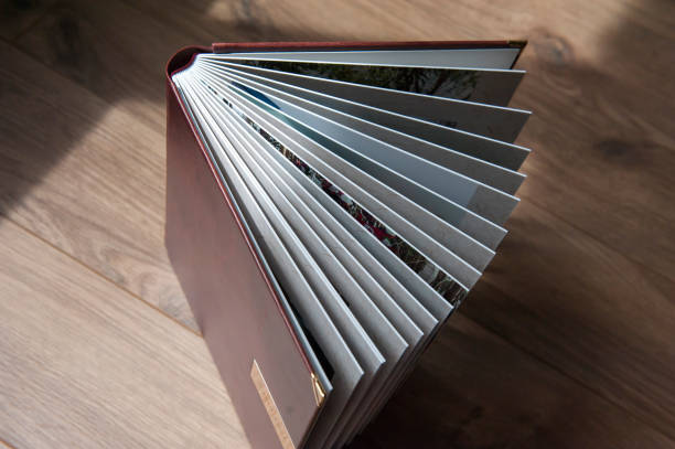 istock Open brown photobook with thick hardback plastic sheets against a wooden table, close-up. View from above 1338041052