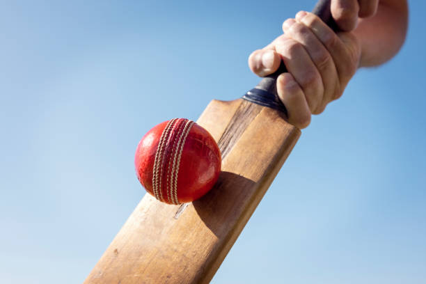 Cricket player batsman hitting a ball with a bat shot from below background Cricket player batsman hitting a ball with a bat shot from below against a blue sky batsman photos stock pictures, royalty-free photos & images